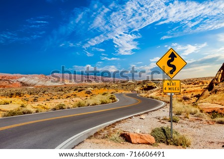 A road sign in the middle of a desert showing curves ahead