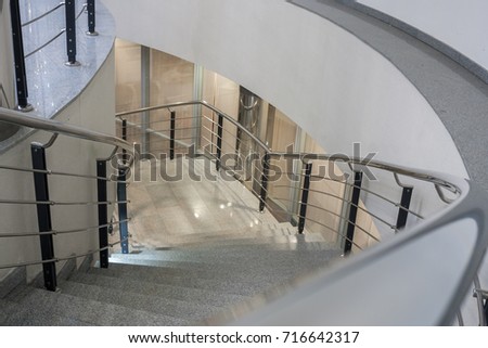 Perspective view down to lit stone spiral staircase with metal railing.