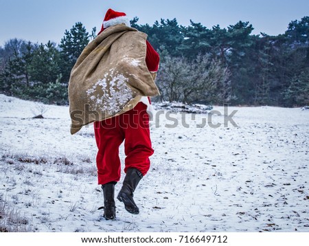 Santa Claus coming to the winter forest with a bag of gifts, snow landscape, Royalty-Free Stock Photo #716649712
