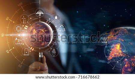 Man holding magnifying glass, search earth with lights in the night of global show the world's consumption with icons energy sources for renewable ecology, Elements of this image furnished by NASA. 
