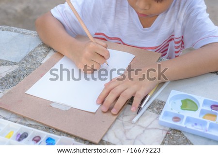 Asian little boy concentrate to drawing, painting and sitting on table