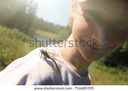 girl teenager with a big dragonfly on her shoulder. bright and juicy summer picture in nature