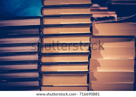 Education and Study as concept, Book stack and blurred bookshelf in the public library room. Vintage retro tone and Selective focus.