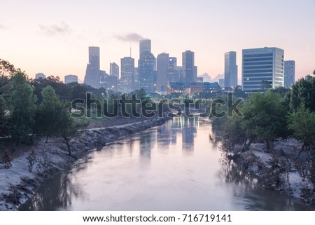 Downtown Houston, Texas, USA skylines city light reflection at sunrise. Eroded stream Buffalo Bayou riverbank with tree roots exposed from undercut of Harvey storm flood. Debris, tree branches downed