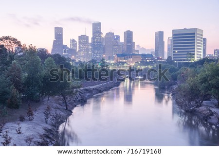 Downtown Houston, Texas, USA skylines city light reflection at sunrise. Eroded stream Buffalo Bayou riverbank with tree roots exposed from undercut of Harvey storm flood. Debris, tree branches downed