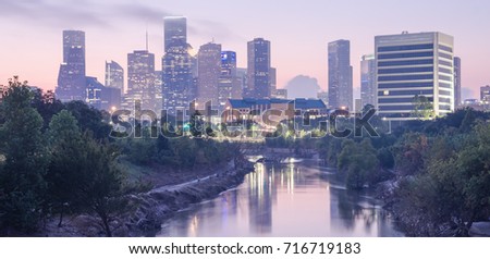 Downtown Houston skylines city light reflection at sunrise. Eroded stream Buffalo Bayou riverbank with tree roots exposed from undercut of Harvey storm flood. Debris, tree branches downed. Panorama