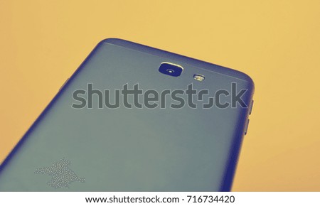 The back of a new smartphone with a camera on a yellow background. Copy space. Modern technology.