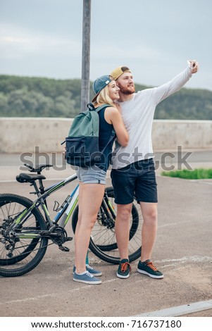 fitness, sport, people, technology and healthy lifestyle concept - happy couple with bicycle taking selfie outdoors