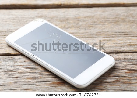 Broken smartphone on a grey wooden table