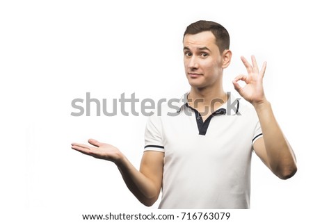 The young man holds copy space and showing ok sign isolated on a white background.