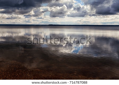 A view of the endless lake with a reflection of clouds.