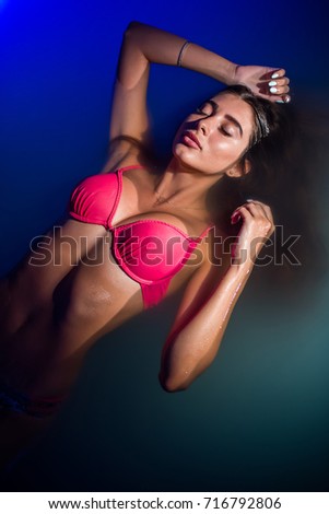 Beautiful tanned woman in pink swimwear relaxing in swimming pool spa