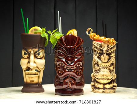 The set of three cocktails with orange and mint in authentic wineglasses in a shape of masks.