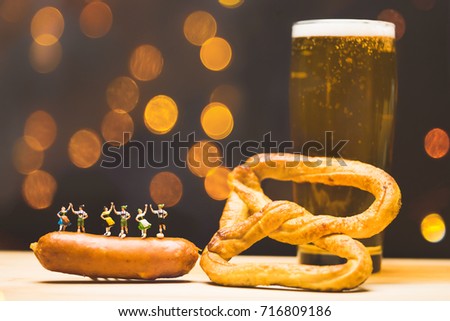 Miniature people.Bavarian man and girl in traditional Dirndl dresses are dancing having fun at the Oktoberfest in sausage and Glass of beer, pretzels background.Oktoberfest Munich in Germany.vintage.
