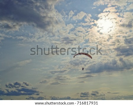 The paraglider flies against the background of the setting sun