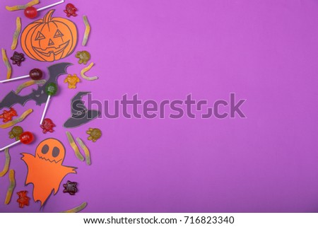 Cloud frame with ghost, candies, pumpkins, spiders and bats cut out of paper. Isolated on purple background.