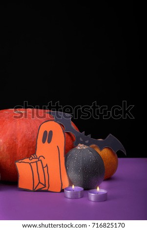 Burning candles. Cloud frame with ghost, pumpkins, spiders and bats cut out of paper. Isolated black background.