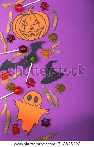 Cloud frame with ghost, candies, pumpkins, spiders and bats cut out of paper. Isolated on purple background.
