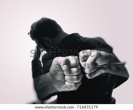 Double exposure image. Silhouette of a man in a business suit are combined with a picture of fists. Concept of confrontation, competition, etc. Black and white image.