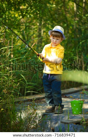Little boy is engaged in fishing in a pond. Child with a dairy in his hands.