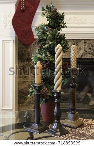 Vertical Christmas display with candles and stocking hung over fireplace