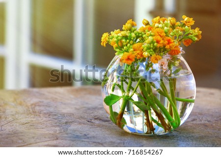 yellow and orange flowers in a round vase on table in street cafe