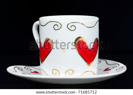 White cup with hearts isolated on black background.