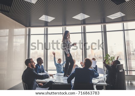picture of happy business team celebrating victory in office. woman stand on table