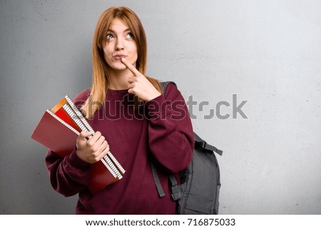 Student woman having doubts on grey background