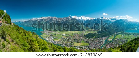 A beautiful view of Interlaken town, Eiger, Mönch and Jungfrau mountains and of Lake Thun and Lake Brienz from Two Lakes Bridge viewing platform on Harder Kulm, Switzerland. Royalty-Free Stock Photo #716879665