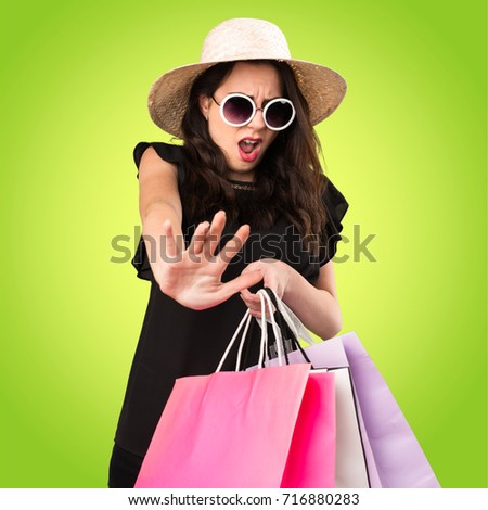 Beautiful young girl  with shopping bag making stop sign on colorful background
