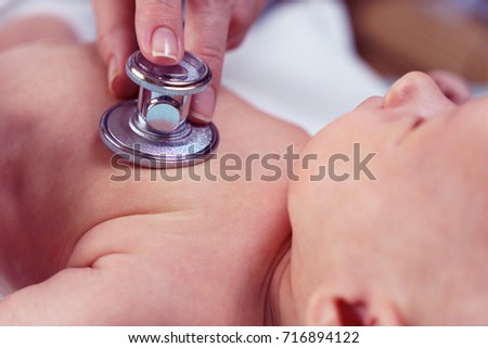 doctor listening heartbeat of newborn baby by stethoscope at day time