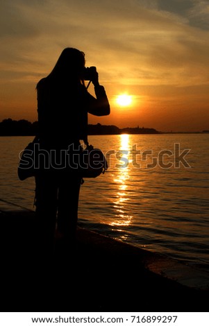     Woman takes pictures of the sunset on the Danube River 