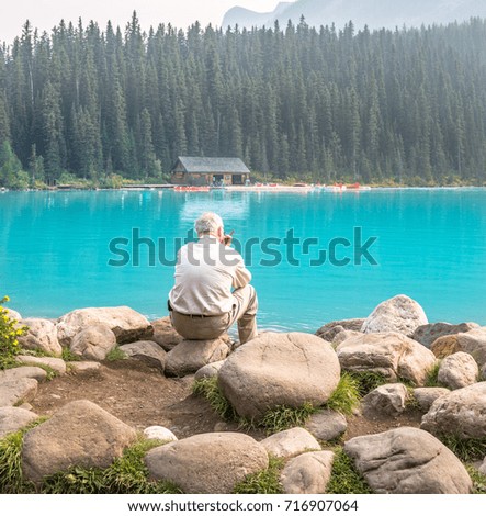 Man sitting at Lake Louise smoking a cigar. 