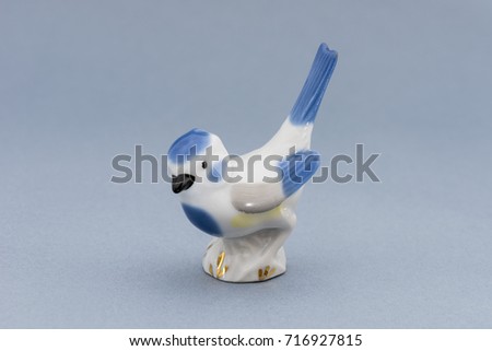 Porcelain bird figure on a gray background.