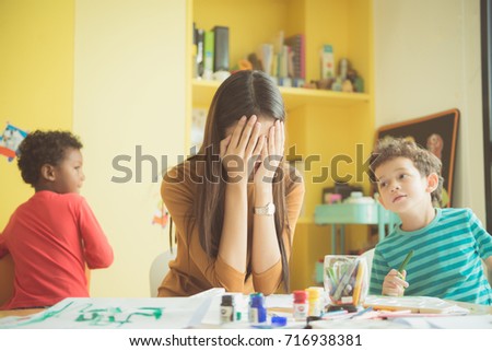Asian teacher kindergarten hands closed both ears of her in an upset of failed to quell quited naughty, of the boys in class at preschool kids argument. Vintage effect style pictures.