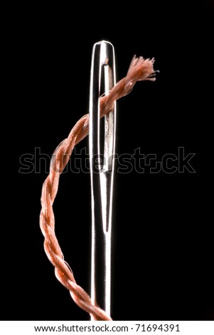Metal needle and string. The string will penetrate into a metal aperture. A black background. Royalty-Free Stock Photo #71694391