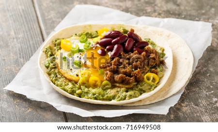 Breakfast taco with guacamole, sunny side up egg, soy meat and kidney beans