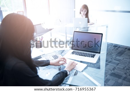  young business women sitting at desk in office.