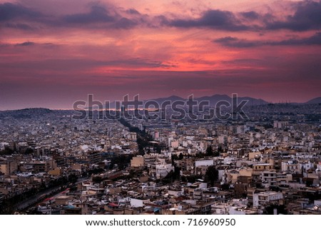Panorama of Athens at sunset. Beautiful cityscape with seashore and distant islands visible under the red sunset sky. Travel photography.