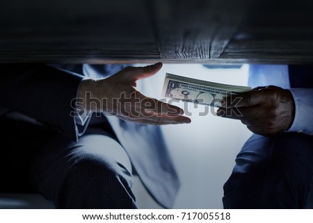 Hands passing money under table corruption bribery Royalty-Free Stock Photo #717005518