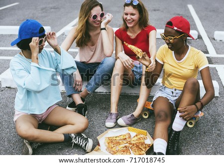 Diverse women sitting on floor eating pizza together
