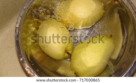 Pears in a bowl under running water.