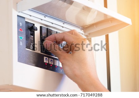 The electrician on hand open circuit breaker board. Selective focus. Royalty-Free Stock Photo #717049288