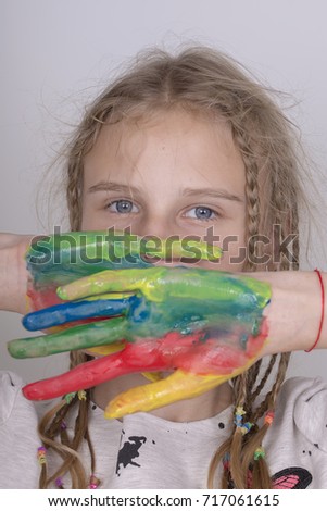 Portrait young girl and hands painted in colorful paints, close up