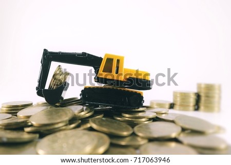Yellow miniature loader construction car carry coins on pile of gold coins and blur rolls ladder of money in white background 