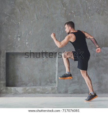 Workout. Male athlete sprinter running, exercising indoors, jogging in training room, side view, full length