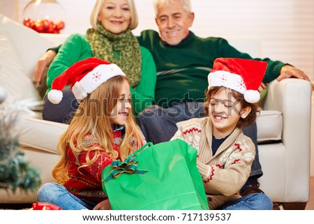 Children at grandfather and grandmother at christmas opening gifts