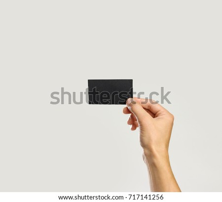 Male hands holding a black sheet of paper. Isolated on gray background. Closeup.