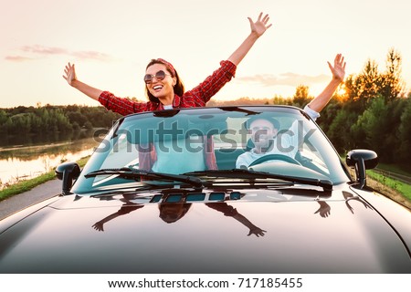 Traveling by car - happy couple in love go by cabriolet car in sunset time Royalty-Free Stock Photo #717185455